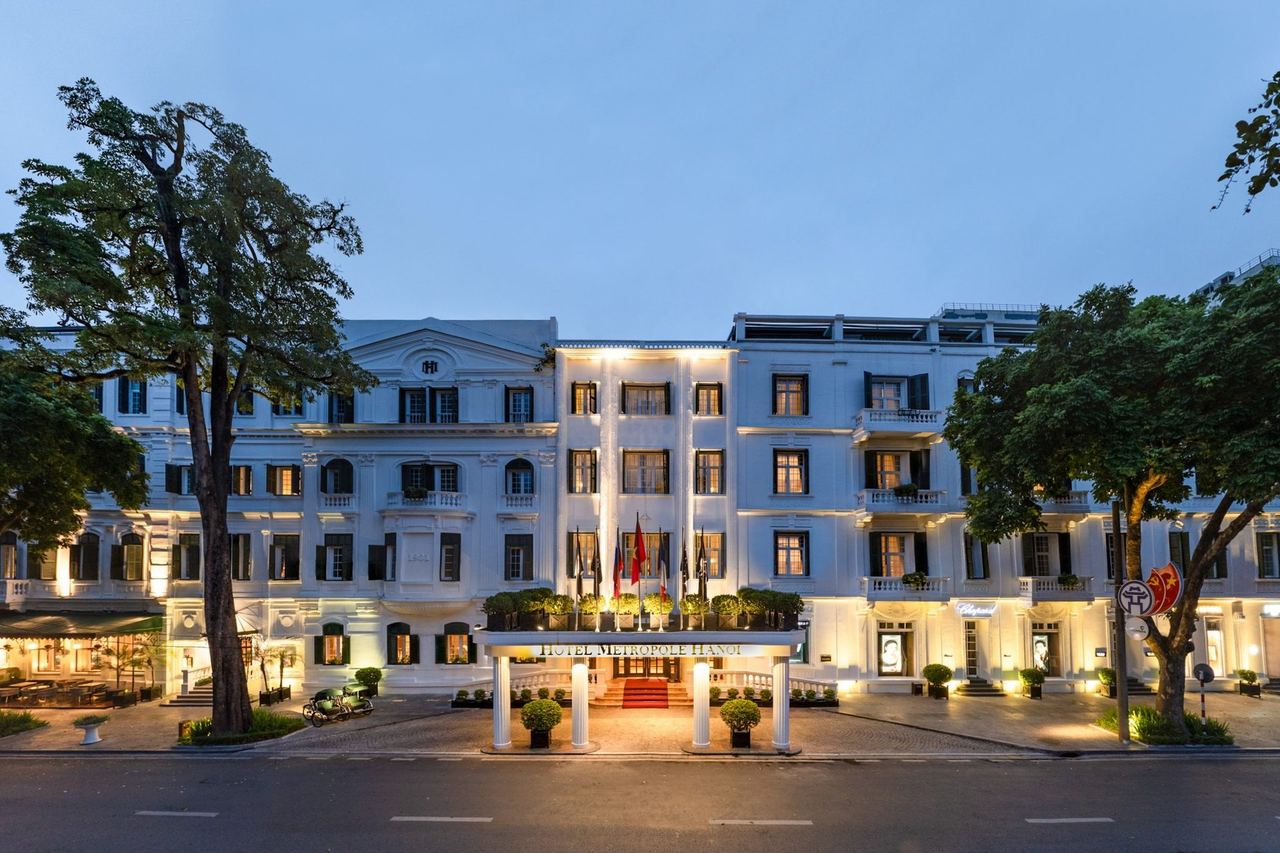 The white façade of the Sofitel Legend Metropole Hanoi lit at dusk on Ngô Quyền